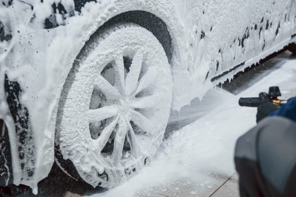 Car in Swindon being cleaned with snow foam, showcasing the thick foam clinging to the vehicle's surface to remove dirt and grime effectively.