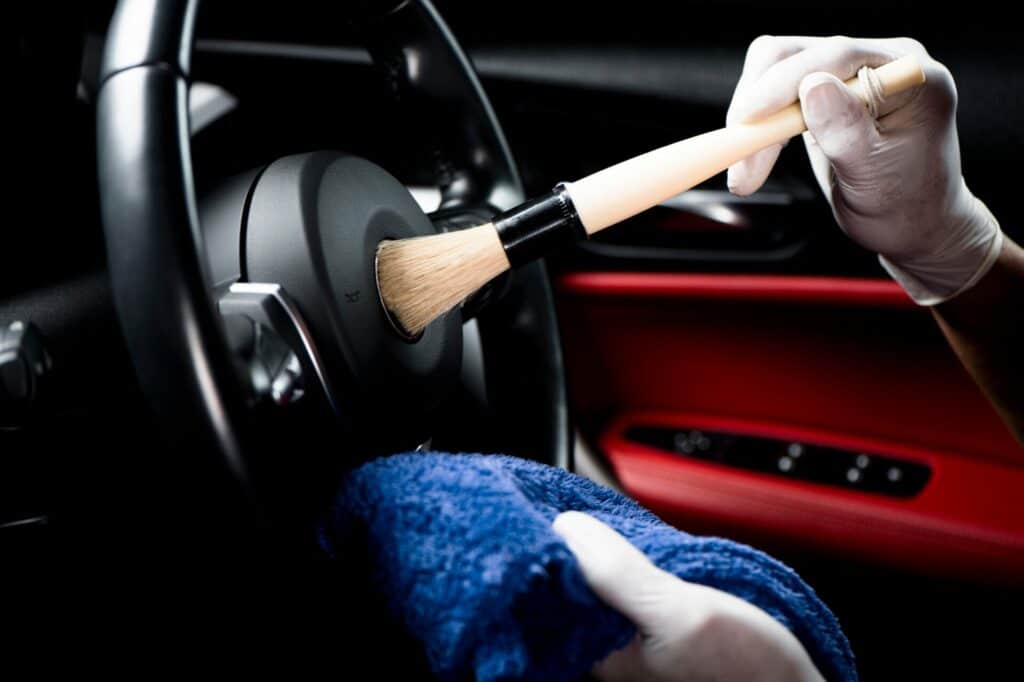 Professional interior car valet service in Swindon, showcasing a technician thoroughly cleaning the car's seats and dashboard for a pristine finish.